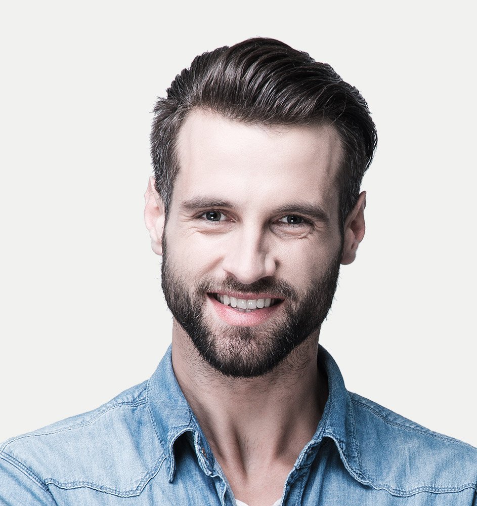 Smiling man with dark hair and beard wearing a light blue denim shirt against a white background